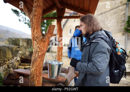 Tourist acqua potabile dal pozzo di Motsameta monastero situato sulla scogliera mozzafiato-alto promontorio al di sopra di un ansa del fiume Tskhaltsitela. Kuta Foto Stock