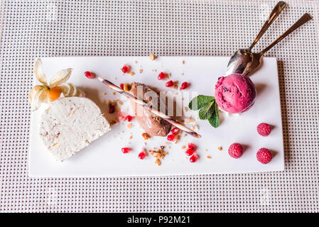 Pezzo di marrone una mousse di cioccolato u dessert e decorazione su una piastra bianca sullo sfondo Foto Stock