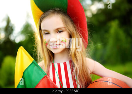 Funny bambina il supporto e il tifo nazionale la sua squadra di basket durante il campionato di pallacanestro. Carino team lituano ventola. Foto Stock