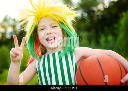 Funny bambina il supporto e il tifo nazionale la sua squadra di basket durante il campionato di pallacanestro. Carino team lituano ventola. Foto Stock