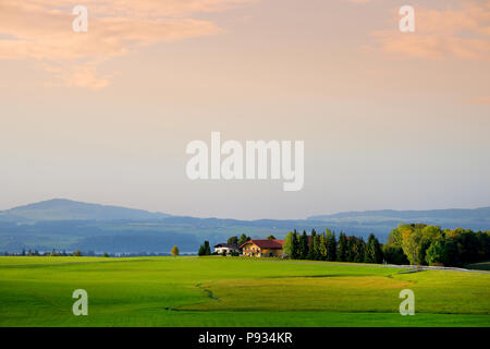 Lansdcape mozzafiato della campagna austriaca sul tramonto. Drammatica cielo sopra idilliaci campi verdi di Anstrian Alpi Centrali su inizio autunno sera. Foto Stock