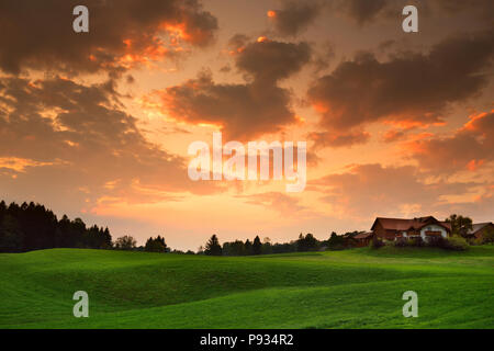 Lansdcape mozzafiato della campagna austriaca sul tramonto. Drammatica cielo sopra idilliaci campi verdi di Anstrian Alpi Centrali su inizio autunno sera. Foto Stock