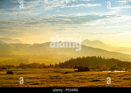 Lansdcape mozzafiato della campagna austriaca sul tramonto. Drammatica cielo sopra idilliaci campi verdi di Anstrian Alpi Centrali su inizio autunno sera. Foto Stock