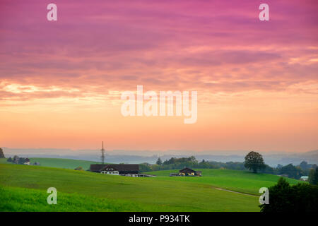 Lansdcape mozzafiato della campagna austriaca sul tramonto. Drammatica cielo sopra idilliaci campi verdi di Anstrian Alpi Centrali su inizio autunno sera. Foto Stock