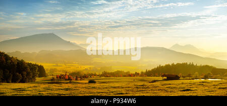 Lansdcape mozzafiato della campagna austriaca sul tramonto. Drammatica cielo sopra idilliaci campi verdi di Anstrian Alpi Centrali su inizio autunno sera. Foto Stock