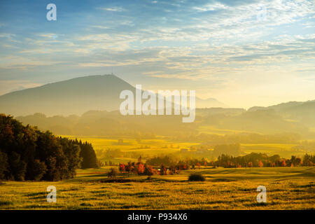 Lansdcape mozzafiato della campagna austriaca sul tramonto. Drammatica cielo sopra idilliaci campi verdi di Anstrian Alpi Centrali su inizio autunno sera. Foto Stock