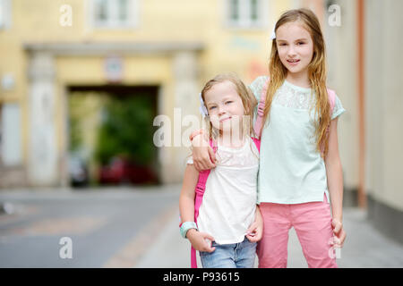 Due graziosi piccole sorelle avente un camminare insieme in una città sul sole e caldo giorno d'estate Foto Stock