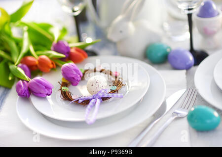 Bella tavola apparecchiata con stoviglie e fiori per la festa di Pasqua. Bicchieri e posate per catering cena evento. Foto Stock