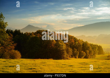 Lansdcape mozzafiato della campagna austriaca sul tramonto. Drammatica cielo sopra idilliaci campi verdi di Anstrian Alpi Centrali su inizio autunno sera. Foto Stock