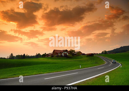 Lansdcape mozzafiato della campagna austriaca sul tramonto. Drammatica cielo sopra idilliaci campi verdi di Anstrian Alpi Centrali su inizio autunno sera. Foto Stock