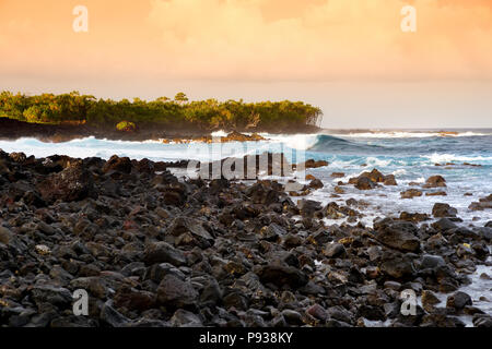 Di un bel colore rosa colorato di onde che si infrangono sulla spiaggia rocciosa di sunrise sulla costa est della Big Island delle Hawaii, STATI UNITI D'AMERICA Foto Stock