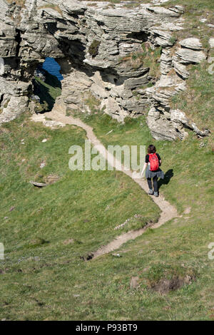 Escursionista femmina camminando lungo la costa sud occidentale il percorso verso il Signore finestra arco di roccia nei pressi di Boscastle in Cornovaglia, England, Regno Unito Foto Stock