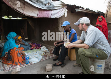 Kakuma, Kenya - Kai Feldhaus, reporter e giornalista del quotidiano Bild in conversazione con una famiglia di rifugiati nel campo di rifugiati di Kakuma. Foto Stock