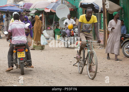 Kakuma, Kenya - Scene di strada con la gente, motociclette e biciclette. Il traffico su una trafficata strada sterrata. Foto Stock