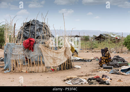 Kakuma, Kenya - Sul bordo del campo profughi di Kakuma. Una donna è perso nella parte anteriore del suo rifugio, coperto con vecchi teloni di plastica. Foto Stock