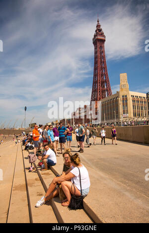 Regno Unito, Inghilterra, Lancashire, Blackpool, Promenade, visitatori sat in sole sulla Scalinata di piazza di Spagna le difese del mare al di sotto della torre Foto Stock