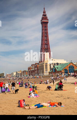 Regno Unito, Inghilterra, Lancashire, Blackpool, visitatori il relax al sole sulla spiaggia al di sotto della Torre di Blackpool Foto Stock