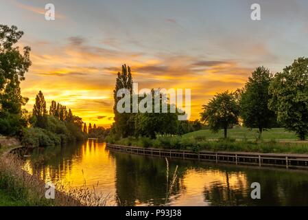 Un tramonto spettacolare su un ansa del fiume Ouse a York. Un percorso corre lungo un viale alberato in riva al fiume. Foto Stock