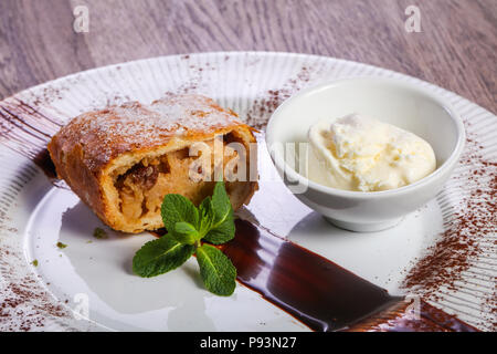 Strudel di mele con gelato servito con foglie di menta Foto Stock