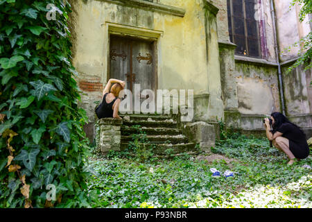 Fotografo presso outdoor è tenuto foto di giovane donna in posa sulla scalinata medioevale. Foto Stock