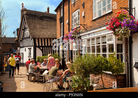 Persone uomini e donne godendo il sole estivo di mangiare e di bere fuori al cafe' sul marciapiede in città mercato di Sandbach in Cheshire England Regno Unito Foto Stock