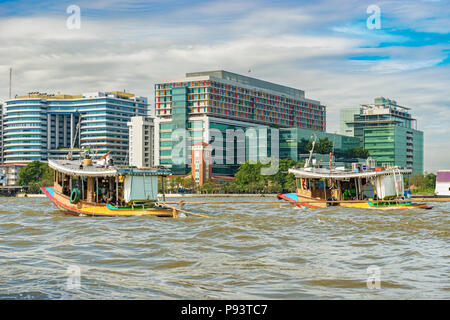 Due locali di barche a motore e le case lungo il fiume Chao Phraya a Bangkok, in Thailandia. Foto Stock