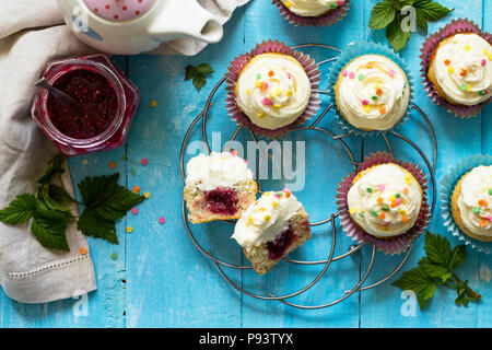 Colorato arancione cupcake compleanno con confettura di lamponi su un tavolo di legno. Vista superiore piatta sullo sfondo dei laici. Foto Stock