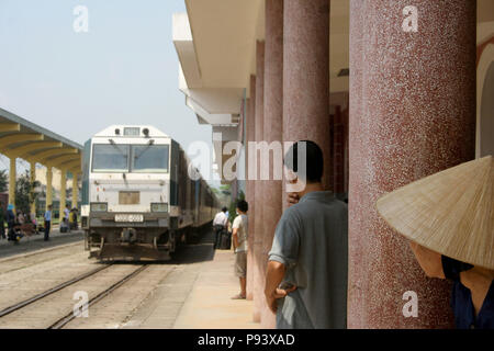 Il vietnamita treno in arrivo nella stazione di Hue con Lady vietnamita nel cappello conico guardando, tonalità, Vietnam Foto Stock