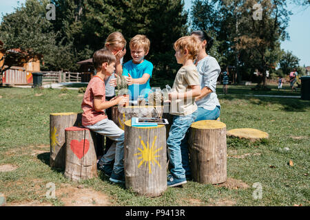 Gruppo di giovani scolari aventi una lezione al di fuori in un parco. I giovani studenti primari ad esplorare le erbe attraverso i loro sensi in un giardino. Foto Stock