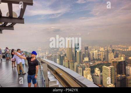 I visitatori sulla sommità della Menara KL Tower con vista del Kuala Lumpur skyline Foto Stock