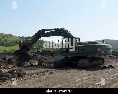 Un rumeno Forze terrestri soldato scava una fossa di scarico utilizzando un escavatore in collaborazione con l'Ingegnere 961st Company, U.S. Esercito di riserva, durante la loro decisa Castello 2018 rotazione in corrispondenza del giunto National Training Centre, Cincu, Romania, Luglio 6, 2018. I due componenti militari hanno lavorato insieme per il cross-treno su apparecchiature e tecnico completo di progetti a sostegno della Atlantic risolvere. (U.S. Esercito nazionale Guard foto di Sgt. 1. Classe Kimberly D. Calkins) Foto Stock