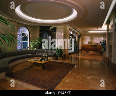 Posti a sedere curvo e oriental tappeto sul pavimento piastrellato in hotel area di ricevimento Foto Stock