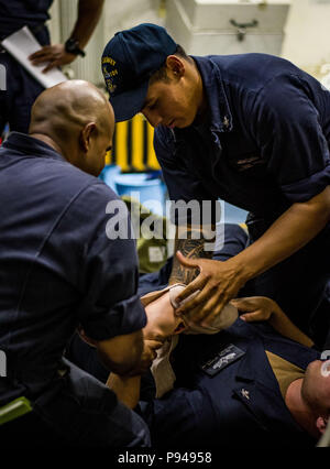 180710-N-LI768-1021 OCEANO PACIFICO (10 luglio 2018) -Boatswain compagno del 3° di classe Edgar Chajon assiste Boatswain compagno del 3° di classe Dalton scintille durante la formazione medica a bordo guidato-missile destroyer USS Dewey (DDG 105). Dewey è in corso la partecipazione nel 2018 Rim del Pacifico (RIMPAC) esercizio. Venticinque nazioni, 46 navi, cinque sommergibili, circa 200 aerei, e 25.000 personale partecipano RIMPAC dal 27 giugno al 2 agosto in e intorno alle Isole Hawaii e la California del Sud. Il più grande del mondo marittimo internazionale esercitazione RIMPAC fornisce un unico opportuni corsi di formazione Foto Stock