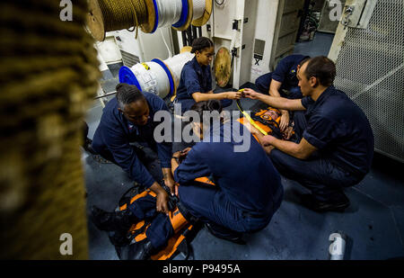 180710-N-LI768-1032 OCEANO PACIFICO (10 luglio 2018) - velisti assegnati alle visite-missile destroyer USS Dewey (DDG 105) sicuro di Boatswain Mate 3° di classe Dalton scintille in una barella durante la formazione medica. Dewey è in corso che partecipano a bordo del Pacifico (RIMPAC) Esercizio 2018. Venticinque nazioni, 46 navi, cinque sommergibili, circa 200 aerei, e 25.000 personale partecipano RIMPAC dal 27 giugno al 2 agosto in e intorno alle Isole Hawaii e la California del Sud. Il più grande del mondo marittimo internazionale esercitazione RIMPAC offre una singolare opportunità di formazione mentre fosterin Foto Stock