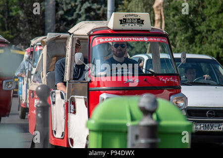 I turisti di esplorare la città europea di Budapest, Ungheria mentre cavalcate in tuk tuks. Foto Stock