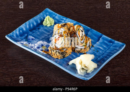 Fritti caldi sushi rotoli su una piastra con salmone e cetrioli su un tavolo di legno. Foto Stock