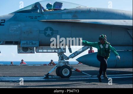 180712-N-OY799-0120 Mare delle Filippine (12 luglio 2018) di aviazione di Boatswain Mate (attrezzature) Airman Olivia Fobbs, da Los Angeles, cancella l'area di varo di un F/A-18E Super Hornet assegnati a Strike Fighter Squadron (VFA) 195 sul ponte di volo della Marina è distribuita portaerei USS Ronald Reagan (CVN 76). Ronald Reagan, il portabandiera del Carrier Strike gruppo 5, fornisce un combattimento-pronto forza che protegge e difende la collettiva degli interessi marittimi dei suoi alleati e partner nella regione Indo-Pacifico. (U.S. Foto di Marina di Massa lo specialista di comunicazione 2a classe Kenneth Abbate/ Foto Stock