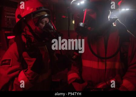 180626-N-UX013-0674 Mare Mediterraneo (26 giugno 2018) dello scafo tecnico di manutenzione di terza classe Sprau Alysa e scafo tecnico di manutenzione di terza classe Hardy Williams valutare un incendio simulato incidente a bordo guidato-missile destroyer USS Jason Dunham (DDG 109) durante un quartieri generali di esercizio. Dunham sta conducendo operazioni navali negli Stati Uniti Sesta flotta area di operazioni a sostegno degli Stati Uniti per gli interessi di sicurezza nazionali in Europa. (U.S. Foto di Marina di Massa lo specialista di comunicazione di terza classe Jonathan argilla/rilasciato) Foto Stock