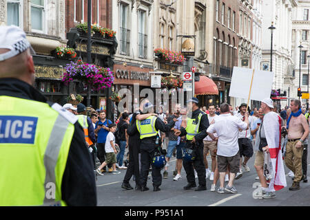 Londra, Regno Unito. 14 Luglio, 2018. I sostenitori di Tommy Robinson, l ex leader della difesa inglese League che era incarcerato nel maggio successivo un disprezzo di corte, tenta invano di convincere la Metropolitan Police officers di posare con un 'Free Tommy' cartellone dopo un rally in Whitehall. Credito: Mark Kerrison/Alamy Live News Foto Stock