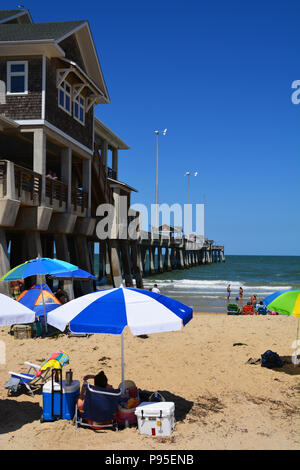 I turisti lay-out sulla spiaggia accanto a Jennette è Pier in Nag testa sul Outer Banks del North Carolina Foto Stock