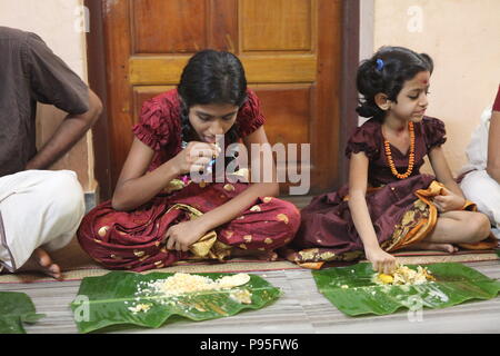 Una famiglia in kerala godendo di una festa in stile tradizionale,seduto sul pavimento,cibo servito su foglie di banana Foto Stock