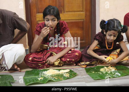 Una famiglia in kerala godendo di una festa in stile tradizionale,seduto sul pavimento,cibo servito su foglie di banana Foto Stock