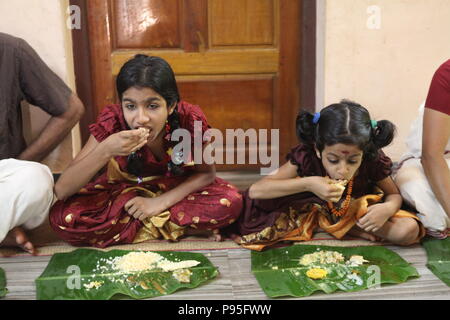 Una famiglia in kerala godendo di una festa in stile tradizionale,seduto sul pavimento,cibo servito su foglie di banana Foto Stock