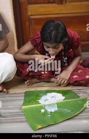 Una famiglia in kerala godendo di una festa in stile tradizionale,seduto sul pavimento,cibo servito su foglie di banana Foto Stock