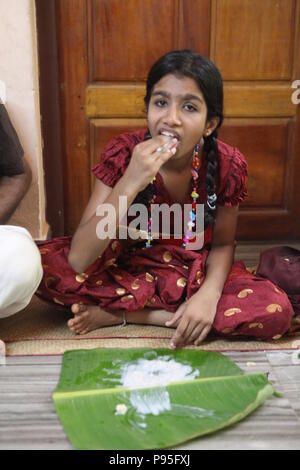 Una famiglia in kerala godendo di una festa in stile tradizionale,seduto sul pavimento,cibo servito su foglie di banana Foto Stock