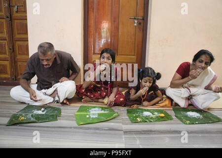 Una famiglia in kerala godendo di una festa in stile tradizionale,seduto sul pavimento,cibo servito su foglie di banana Foto Stock