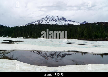 Vista di Mt. Ranieri a riflessione laghi che sono parzialmente congelato, inizio di estate, il Parco Nazionale del Monte Rainier, WA, Stati Uniti d'America. Foto Stock