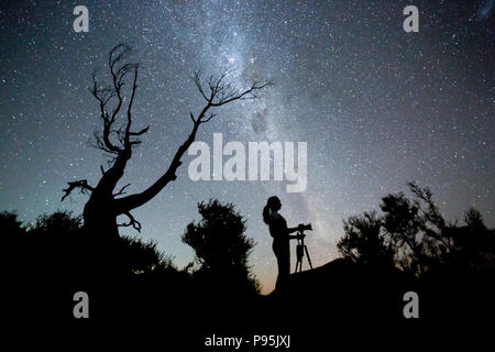 Donna prendendo fotografie sotto un cielo stellato, Nuova Zelanda Foto Stock