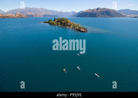 Antenna di stand up paddle boarders paddling a Ruby isola sul lago Wanaka, Nuova Zelanda Foto Stock