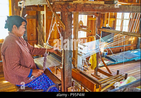 INPAWKHON, MYANMAR - 18 febbraio 2018: Il lavoratore di officina tessile a tessuti prodotti su telai a mano, rendendo lotus tessuto di filati fatti a mano, il 18 febbraio in Foto Stock